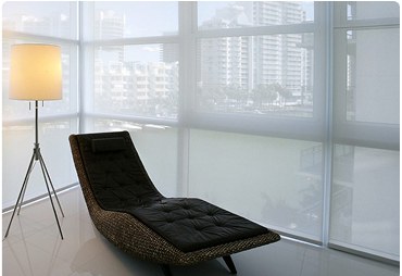 Lounge chair beside a corner window fitted with light-filtering solar shades