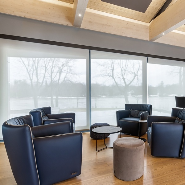 Motorized indoor roller shades across a wall of windows in a modern living room